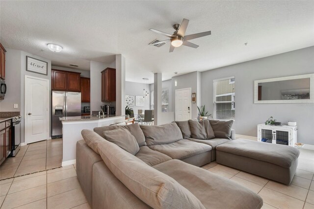 living room featuring ceiling fan, light tile patterned floors, and a textured ceiling