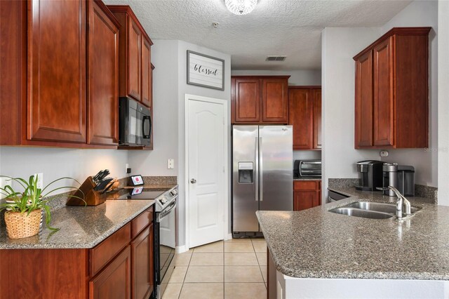 kitchen with light tile patterned floors, a textured ceiling, stainless steel appliances, and sink