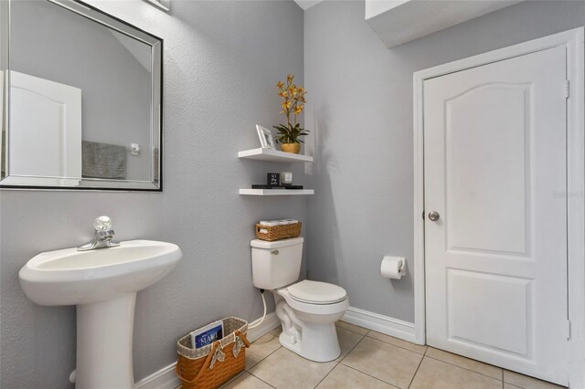 bathroom with toilet, tile patterned floors, and sink