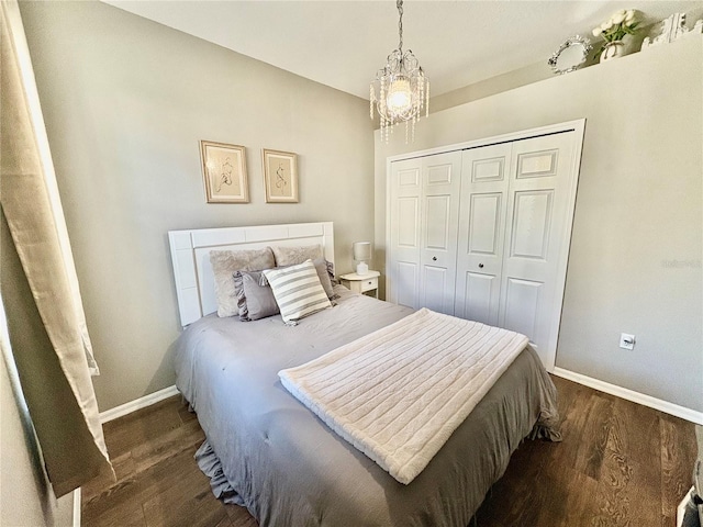 bedroom featuring an inviting chandelier, dark wood-type flooring, and a closet