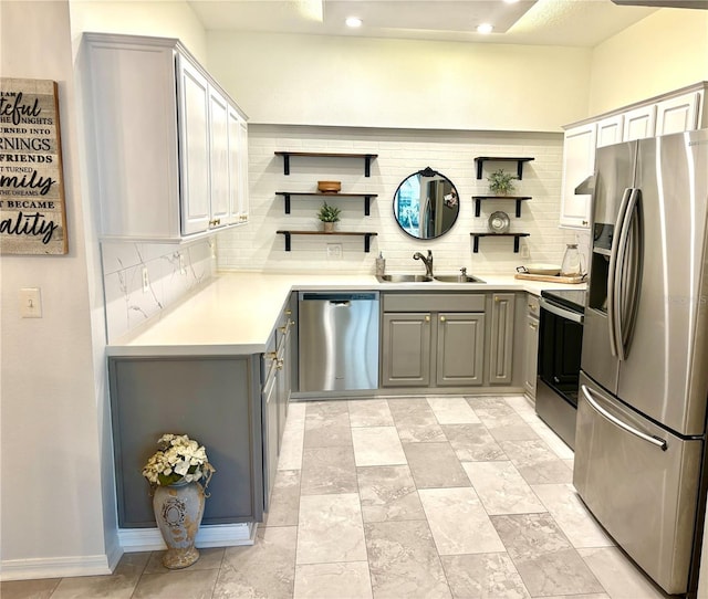 kitchen with gray cabinets, decorative backsplash, sink, and stainless steel appliances