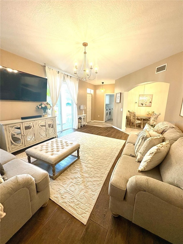 living room featuring dark hardwood / wood-style floors, a textured ceiling, and an inviting chandelier