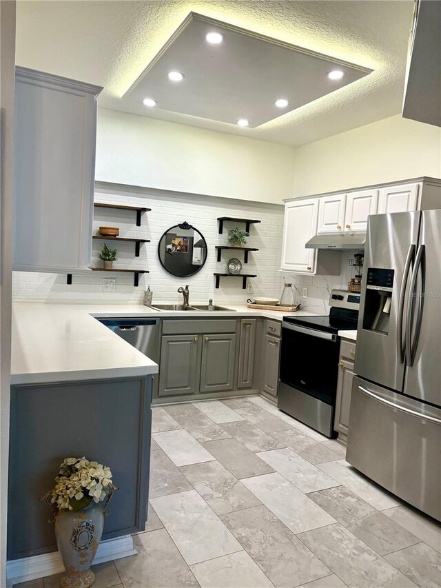 kitchen featuring appliances with stainless steel finishes, backsplash, gray cabinets, and sink