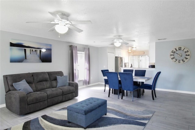 living room with a textured ceiling, ceiling fan, light hardwood / wood-style flooring, and plenty of natural light