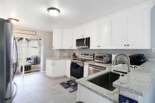 kitchen with white cabinetry, sink, stainless steel appliances, light stone counters, and light hardwood / wood-style floors