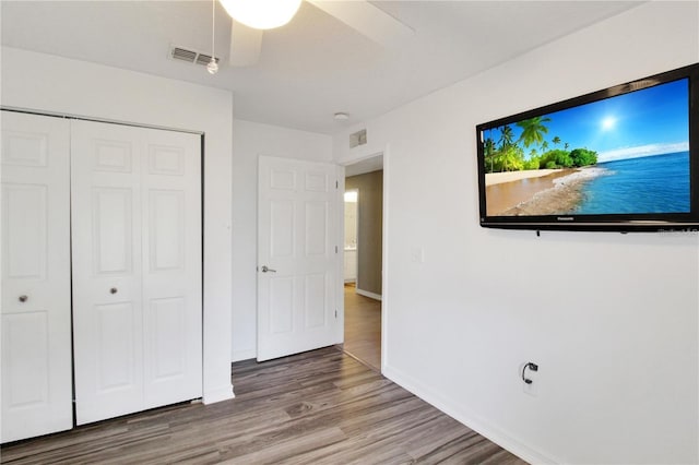 unfurnished bedroom featuring ceiling fan, a closet, and wood-type flooring