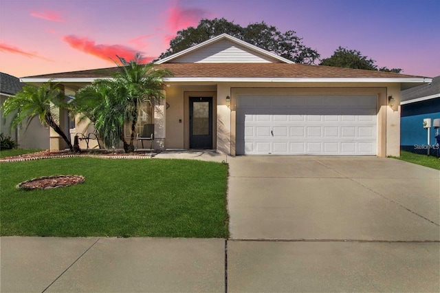 ranch-style home with concrete driveway, a front yard, roof with shingles, stucco siding, and an attached garage