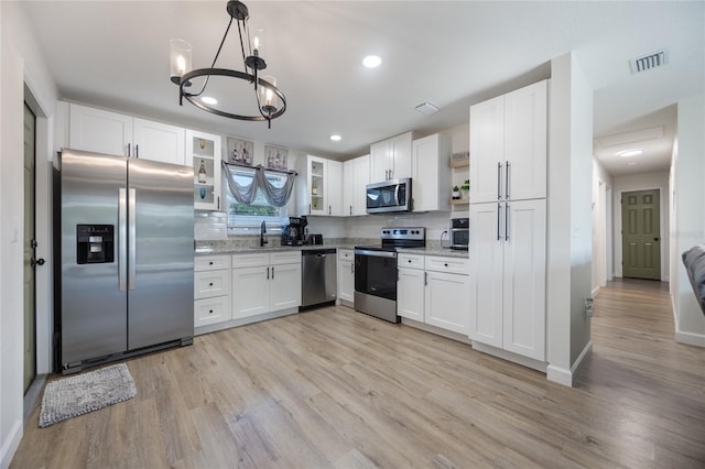 kitchen with pendant lighting, white cabinets, stainless steel appliances, and a notable chandelier