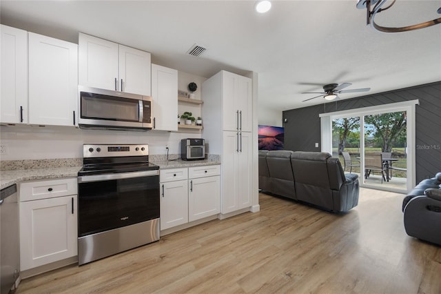 kitchen with white cabinets, light wood-type flooring, and appliances with stainless steel finishes