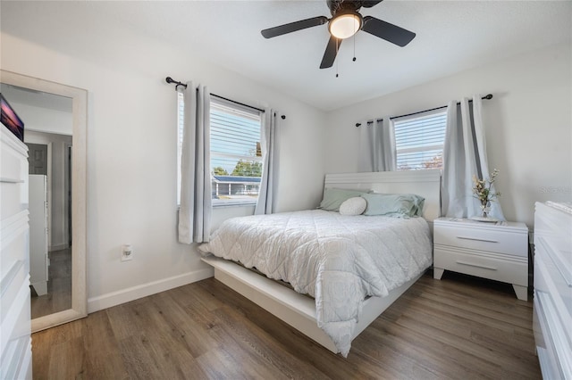 bedroom featuring ceiling fan, dark wood-type flooring, and multiple windows