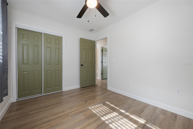 unfurnished bedroom featuring ceiling fan, wood-type flooring, and a closet