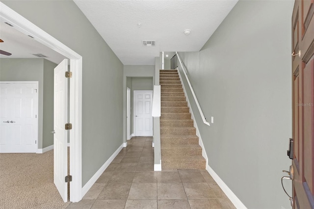 entryway with a textured ceiling and light colored carpet