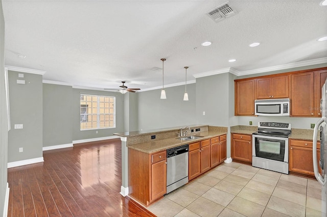 kitchen featuring kitchen peninsula, stainless steel appliances, ceiling fan, sink, and hanging light fixtures