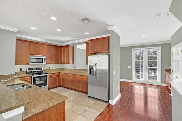 kitchen with french doors, sink, light stone countertops, ornamental molding, and appliances with stainless steel finishes