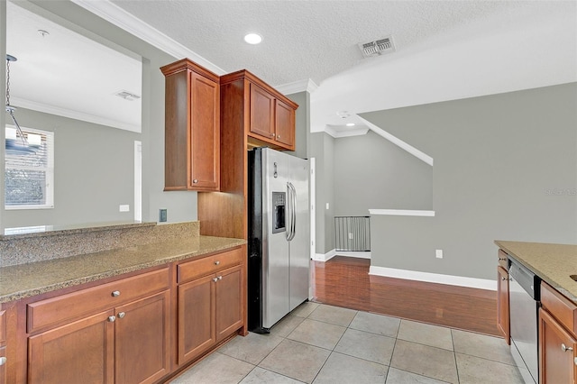 kitchen featuring crown molding, light stone countertops, a textured ceiling, light tile patterned floors, and appliances with stainless steel finishes