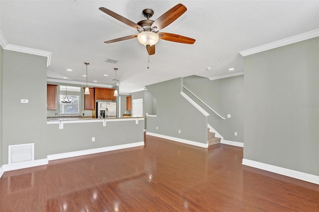 unfurnished living room featuring a textured ceiling, ceiling fan with notable chandelier, and ornamental molding