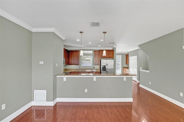 kitchen with kitchen peninsula, decorative light fixtures, stainless steel appliances, and a breakfast bar area