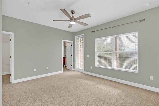 unfurnished bedroom with a walk in closet, ceiling fan, and light carpet