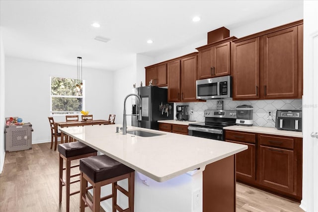 kitchen featuring hanging light fixtures, a breakfast bar, a center island with sink, and stainless steel appliances