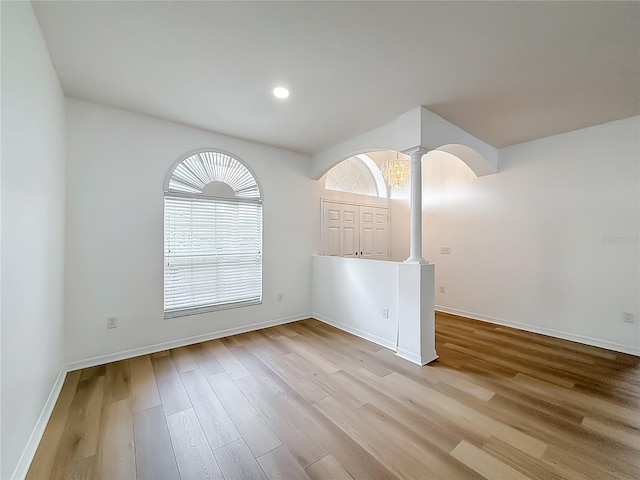 empty room with light hardwood / wood-style flooring and ornate columns