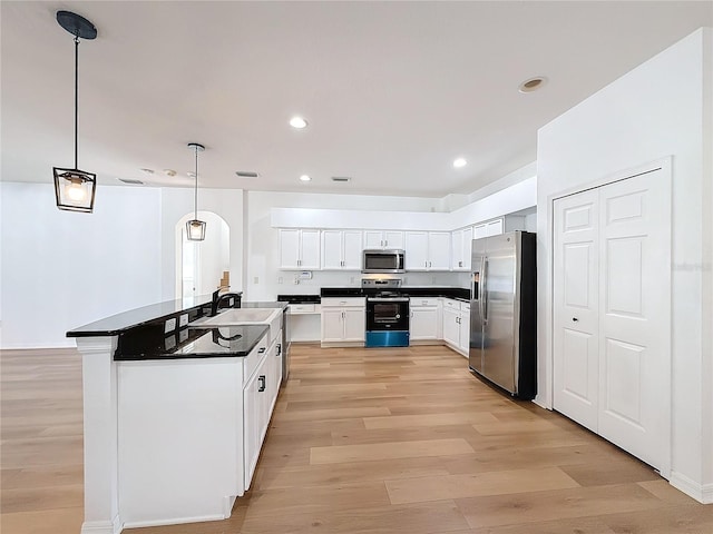 kitchen with sink, hanging light fixtures, light wood-type flooring, white cabinetry, and stainless steel appliances