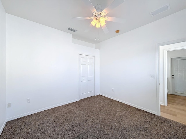 empty room featuring ceiling fan and dark carpet