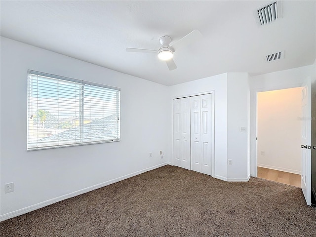 unfurnished bedroom with dark colored carpet, ceiling fan, and a closet