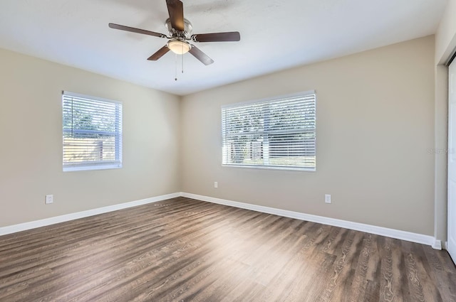 empty room with dark hardwood / wood-style flooring, ceiling fan, and a wealth of natural light