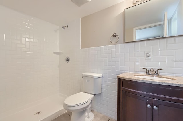 bathroom featuring toilet, tiled shower, vanity, tile patterned floors, and tile walls