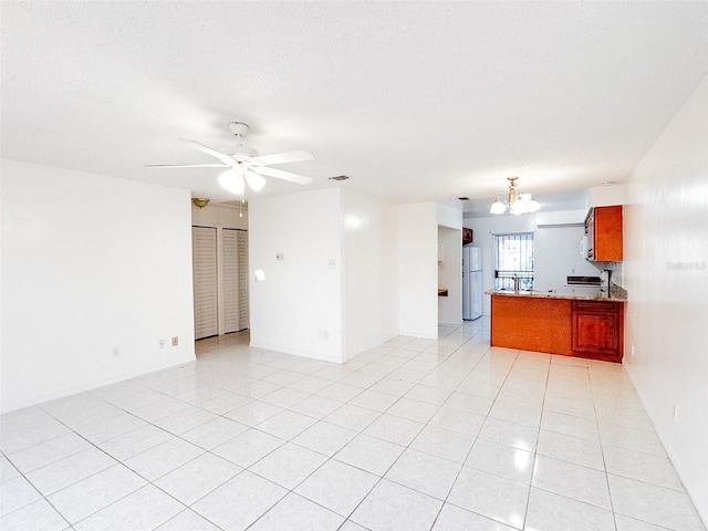 unfurnished living room with ceiling fan with notable chandelier and light tile patterned flooring