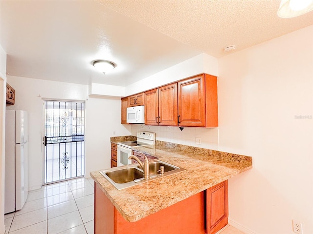 kitchen with white appliances, sink, a textured ceiling, light tile patterned flooring, and kitchen peninsula