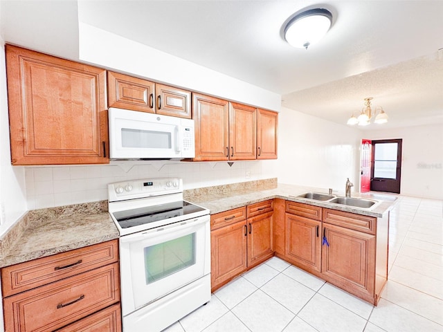 kitchen featuring white appliances, an inviting chandelier, sink, light tile patterned floors, and kitchen peninsula