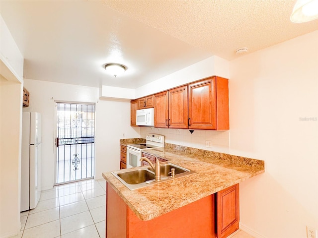 kitchen featuring kitchen peninsula, white appliances, a textured ceiling, sink, and light tile patterned floors