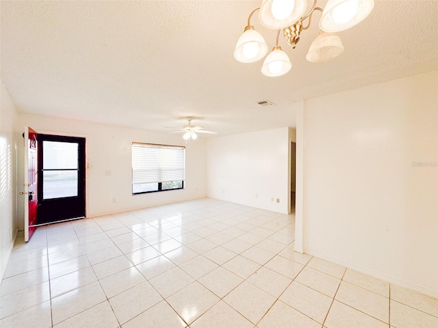 tiled empty room with ceiling fan with notable chandelier and a textured ceiling