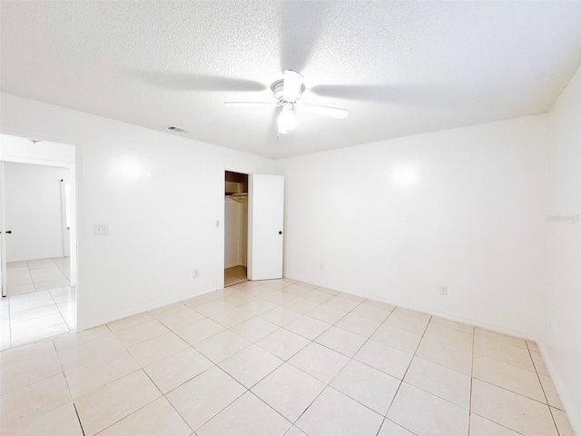 spare room with a textured ceiling, ceiling fan, and light tile patterned flooring