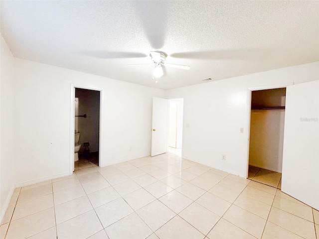 unfurnished bedroom with a textured ceiling, connected bathroom, ceiling fan, and light tile patterned flooring