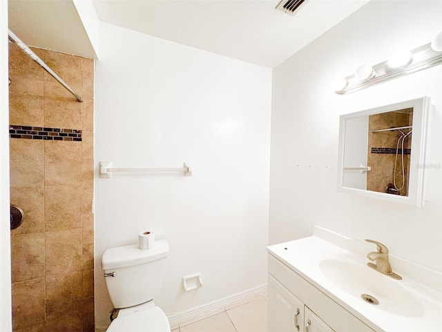 bathroom with toilet, a tile shower, vanity, and tile patterned floors