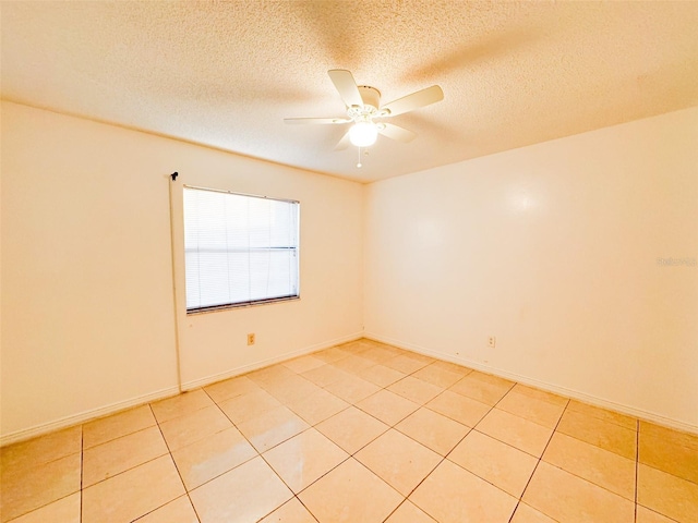 empty room with ceiling fan, light tile patterned flooring, and a textured ceiling