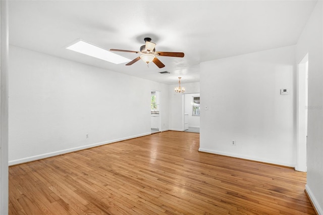 unfurnished room with ceiling fan with notable chandelier and light hardwood / wood-style floors