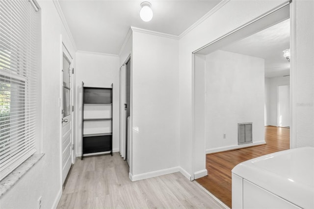 corridor with light hardwood / wood-style flooring and ornamental molding