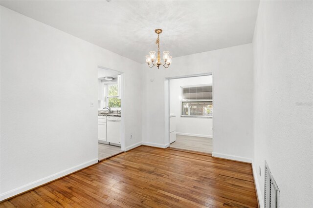 unfurnished dining area with wood-type flooring and a notable chandelier