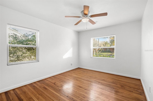 empty room with ceiling fan, plenty of natural light, and wood-type flooring