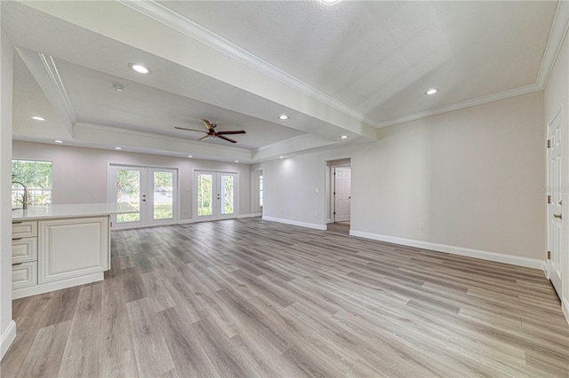 unfurnished living room featuring french doors, a tray ceiling, and a healthy amount of sunlight