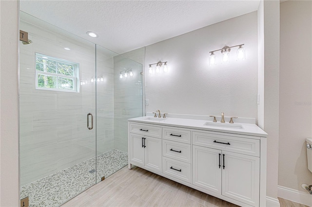 bathroom featuring hardwood / wood-style flooring, vanity, an enclosed shower, and a textured ceiling