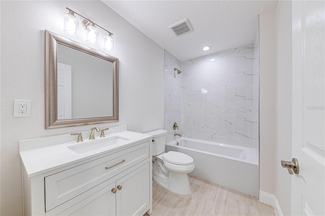 full bathroom with vanity, a textured ceiling, wood-type flooring, toilet, and tiled shower / bath