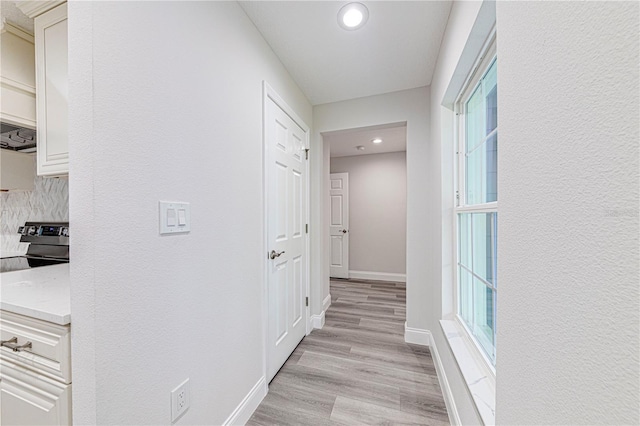 hallway with a wealth of natural light and light hardwood / wood-style floors