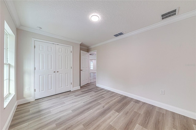 unfurnished bedroom with multiple windows, a textured ceiling, and a closet