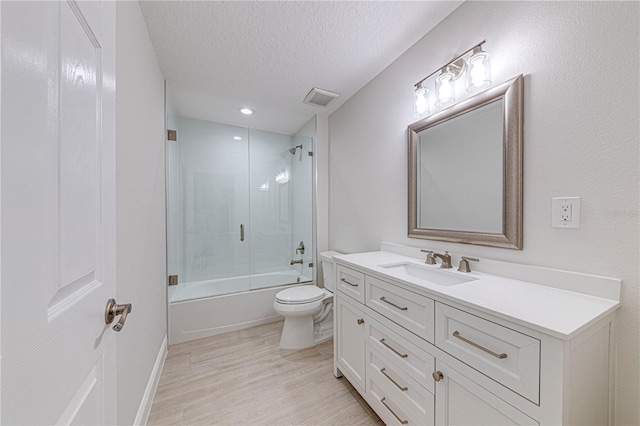 full bathroom featuring vanity, shower / bath combination with glass door, toilet, a textured ceiling, and wood-type flooring