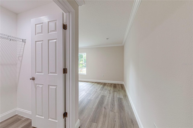 corridor with light hardwood / wood-style floors and crown molding