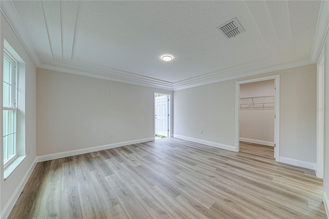 unfurnished bedroom featuring light wood-type flooring, a walk in closet, multiple windows, and a closet